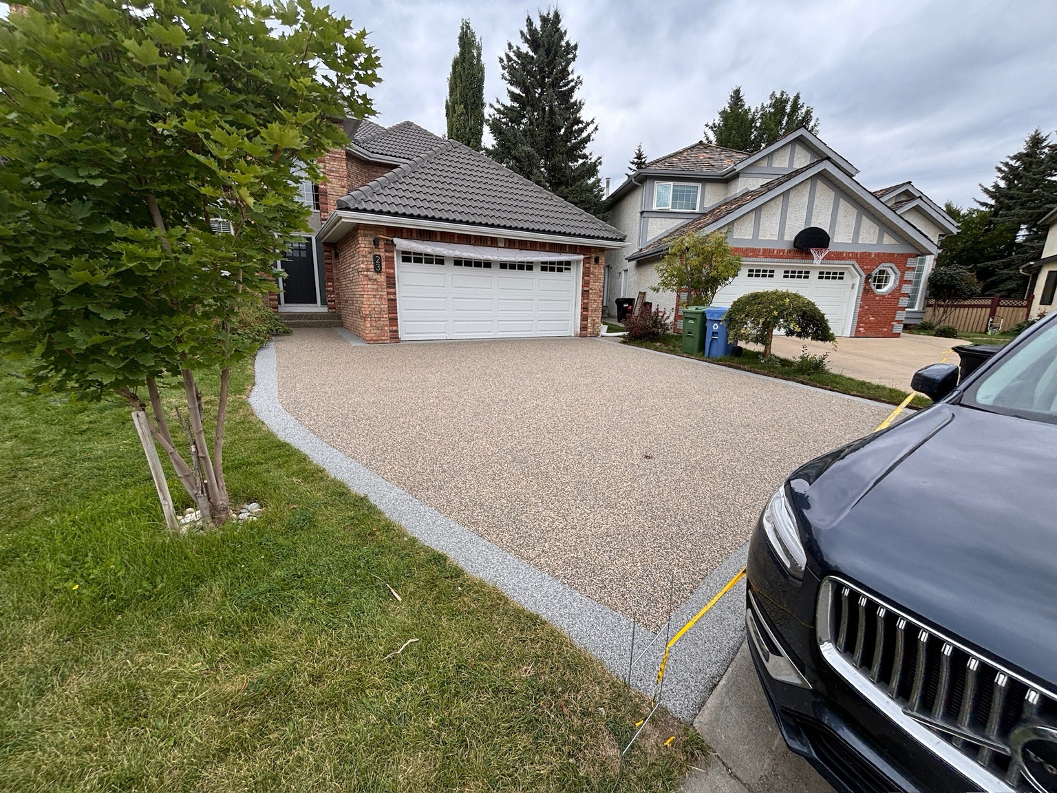 A light natural stone driveway with a curved border leading to a garage