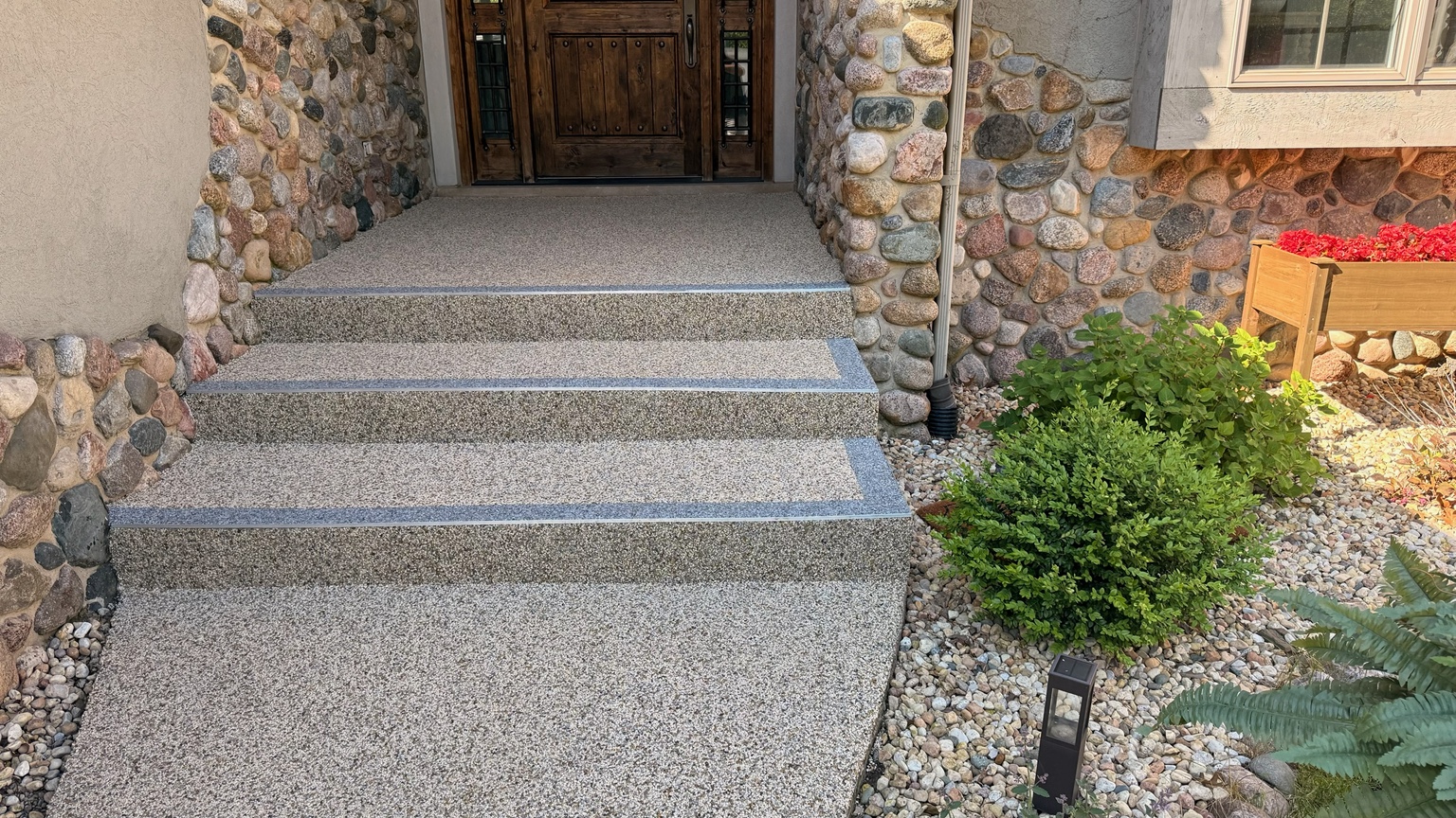 A stone-coated front walkway and steps with contrasting borders