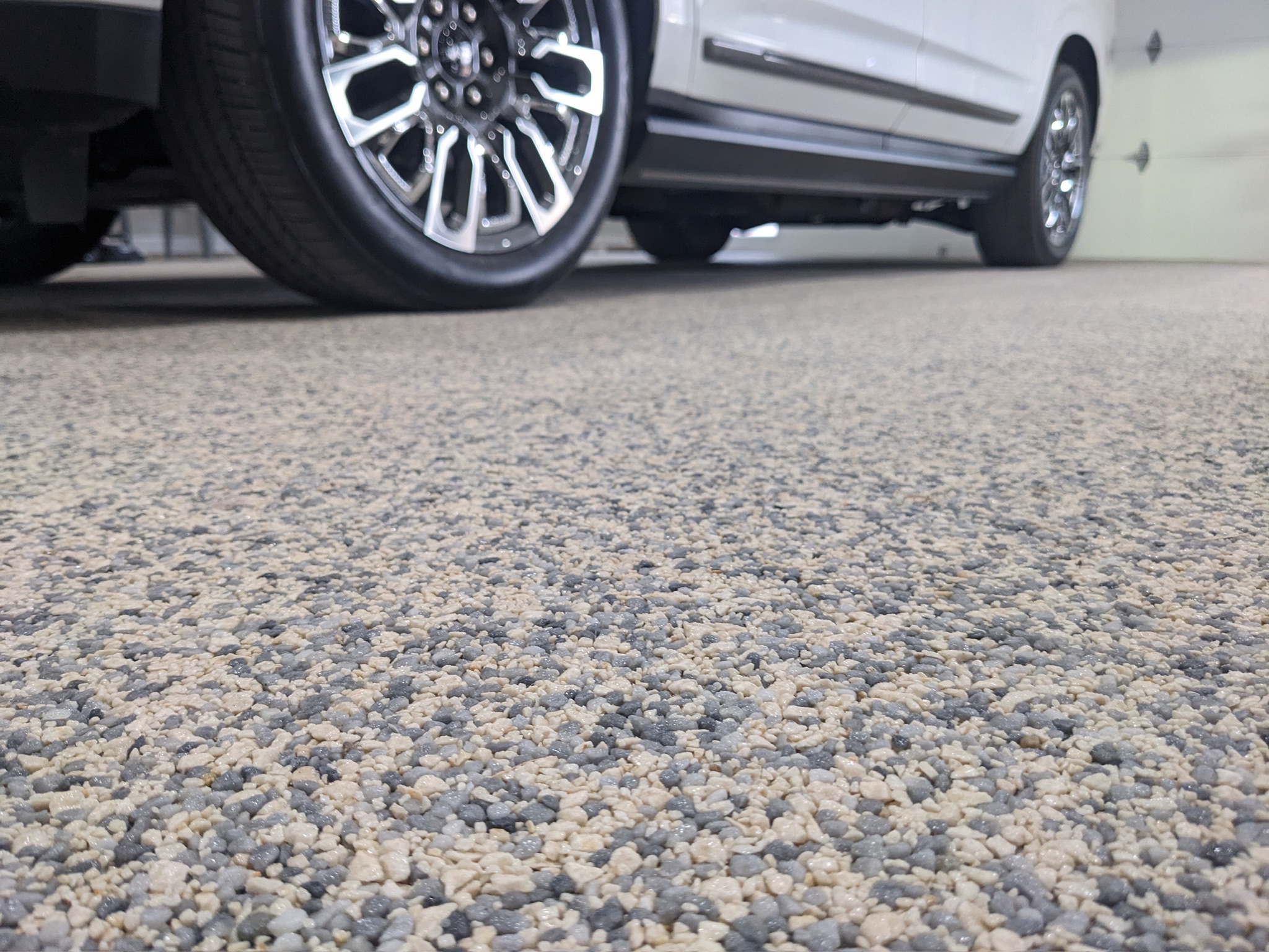Close-up of a natural aggregate garage floor beneath a parked vehicle