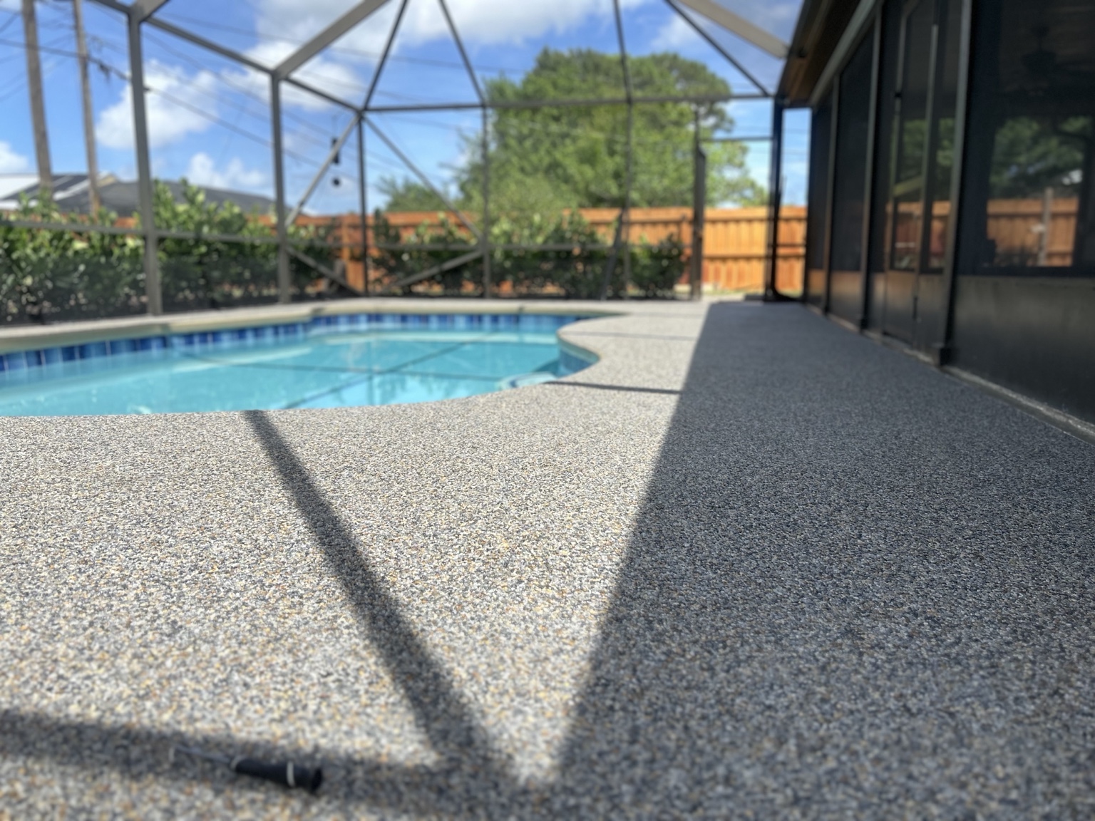 Resin-bound stone surrounding a swimming pool inside a screened lanai
